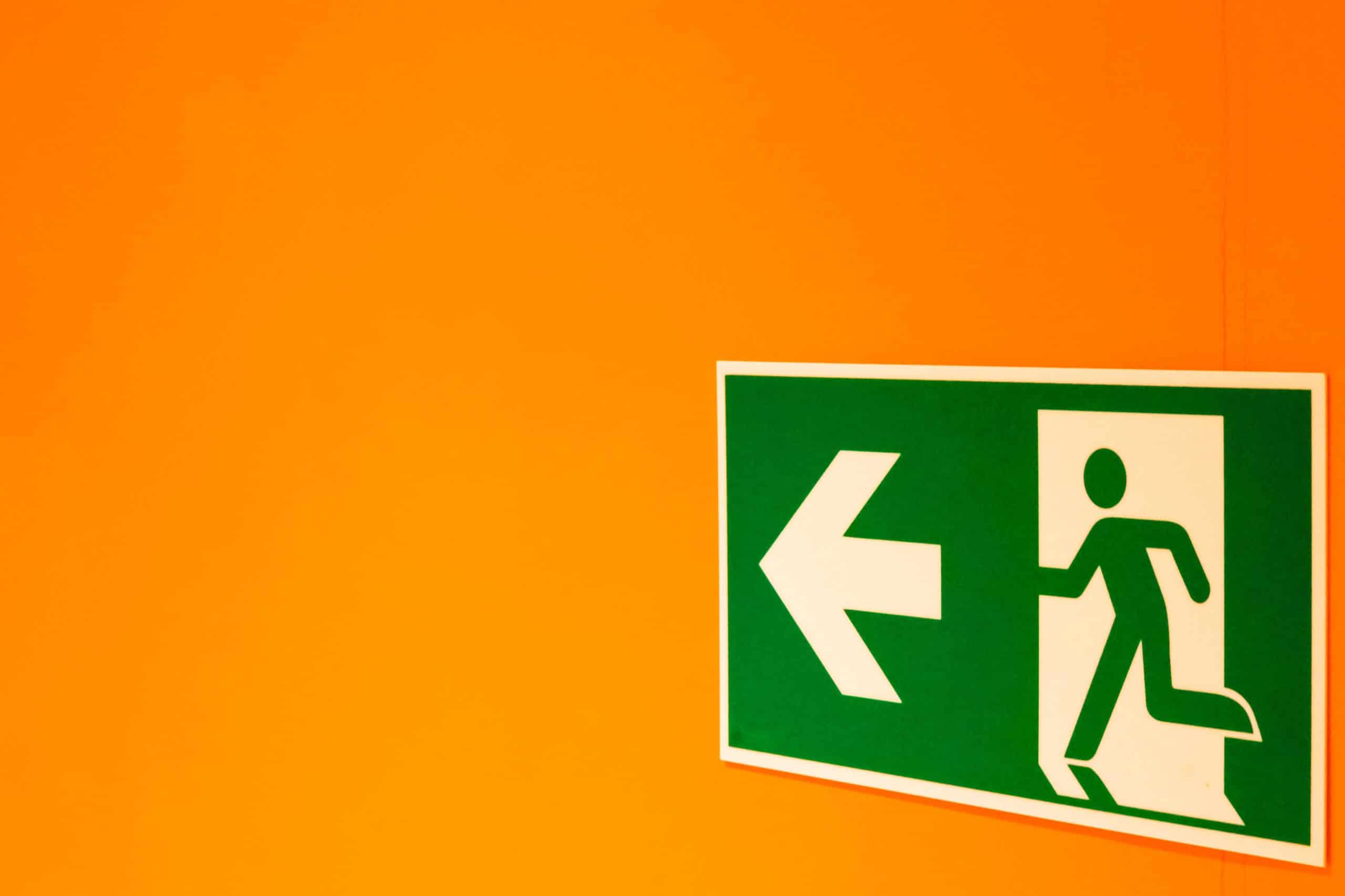 green escape route sign on an orange wall