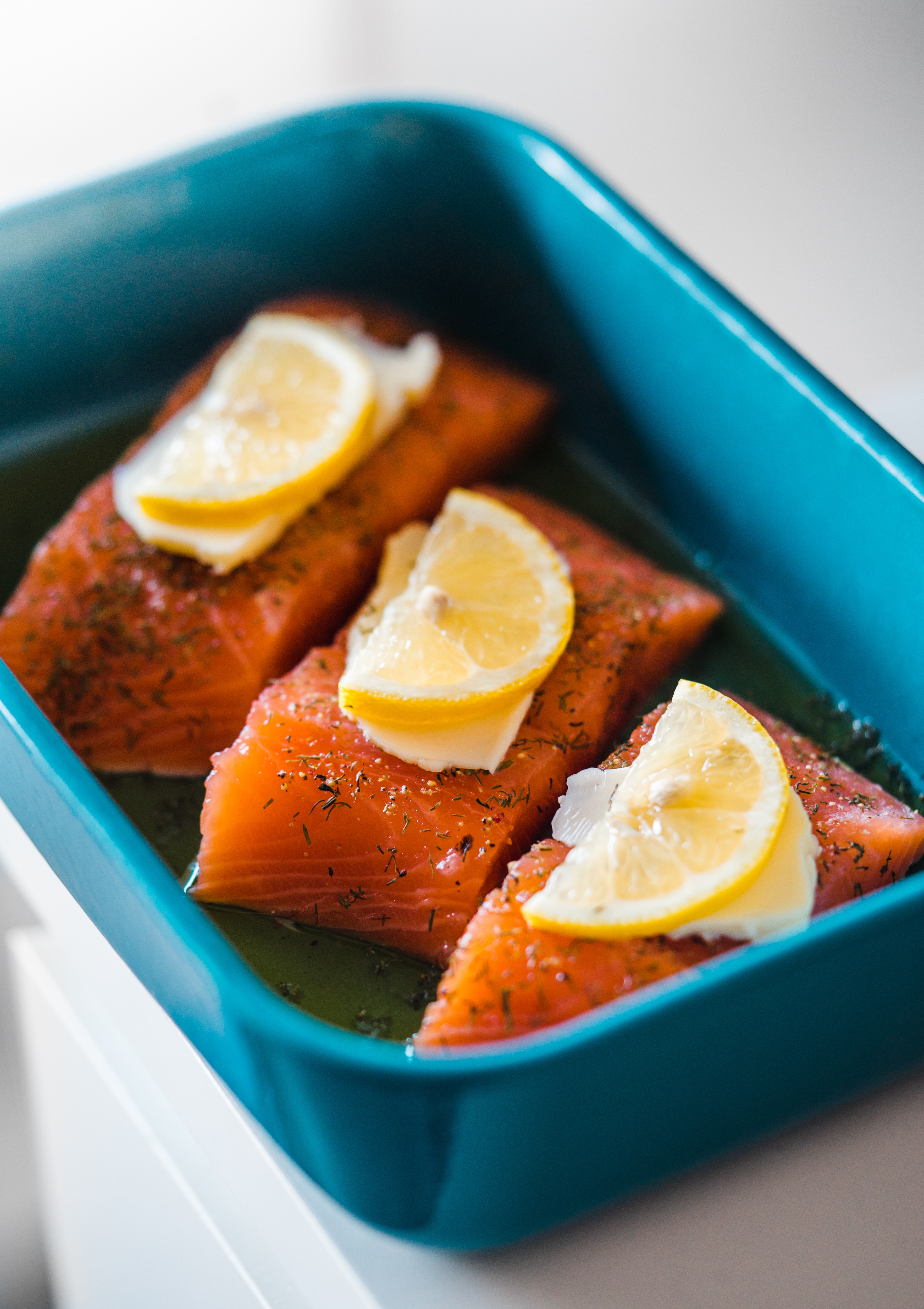 Salmon baking in a blue dish with lemon garnish