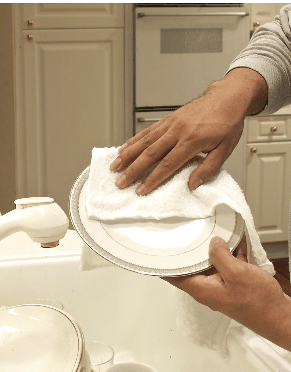 hand washing dishes with a cloth kitchen towel