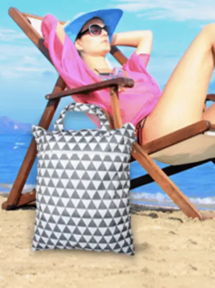 Woman sitting on beach next to a Wet/Dry Bag