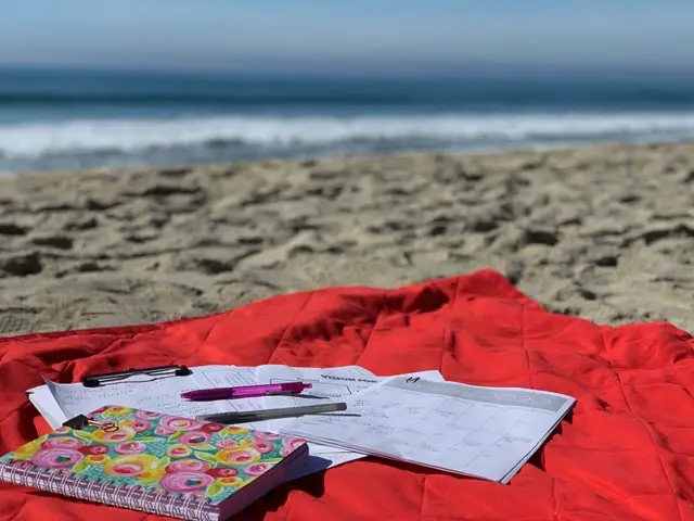 red blanket on a beach with calendar and papers