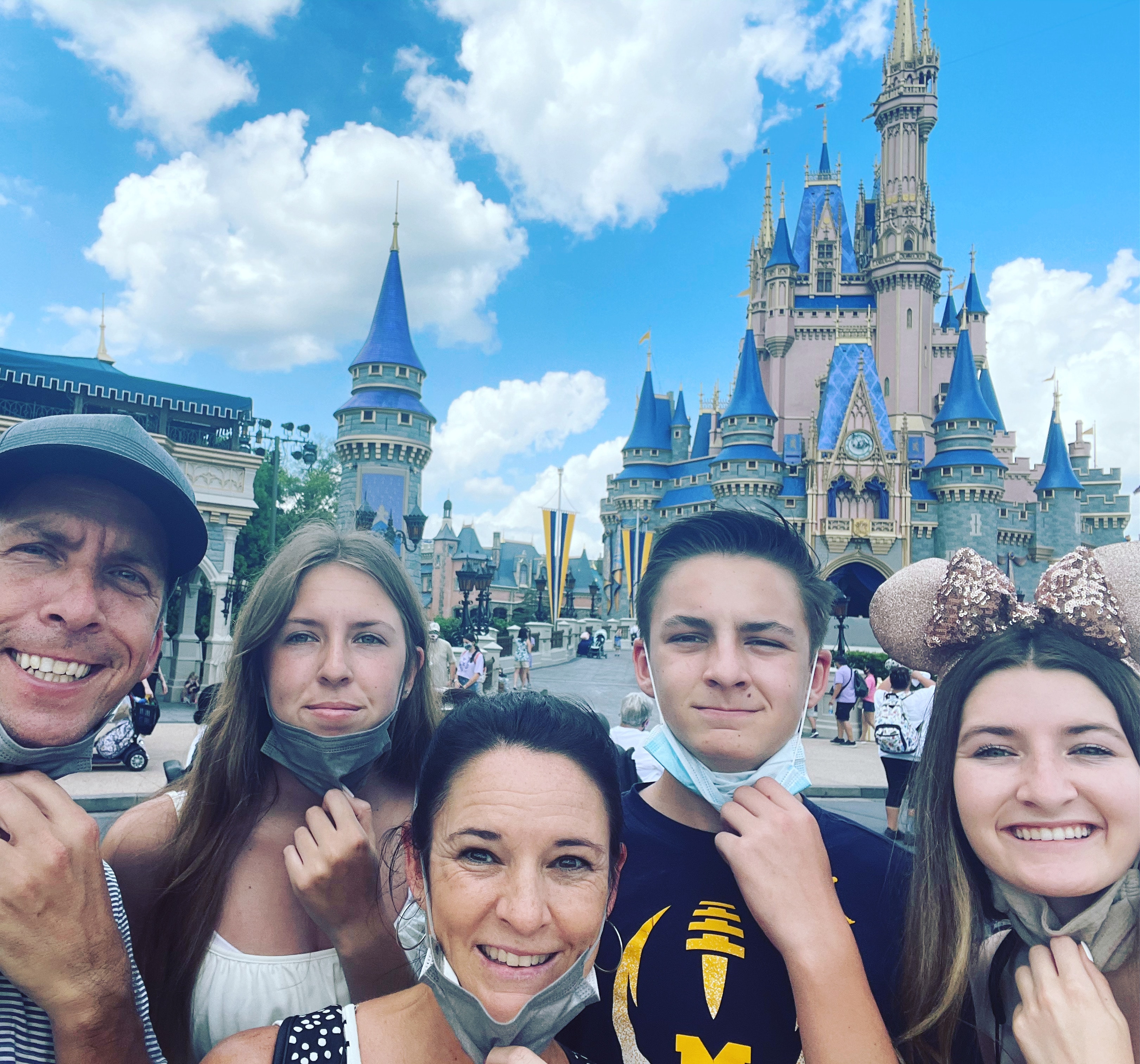 Family at Walt Disney World smiling with face masks pulled down