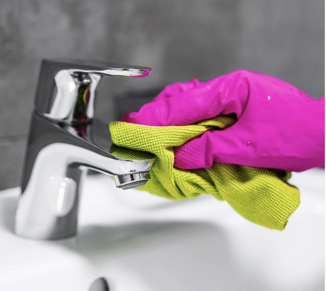 gloved hand cleaning a sink faucet