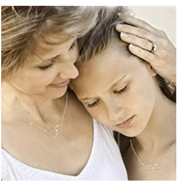 Mother hugging daughter wearing matching necklaces