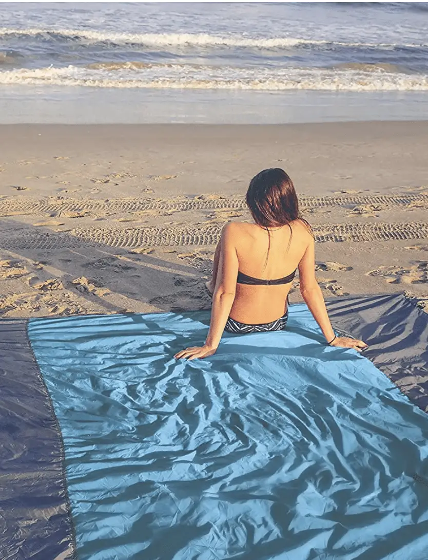 Woman sitting on beach blanket looking at ocean