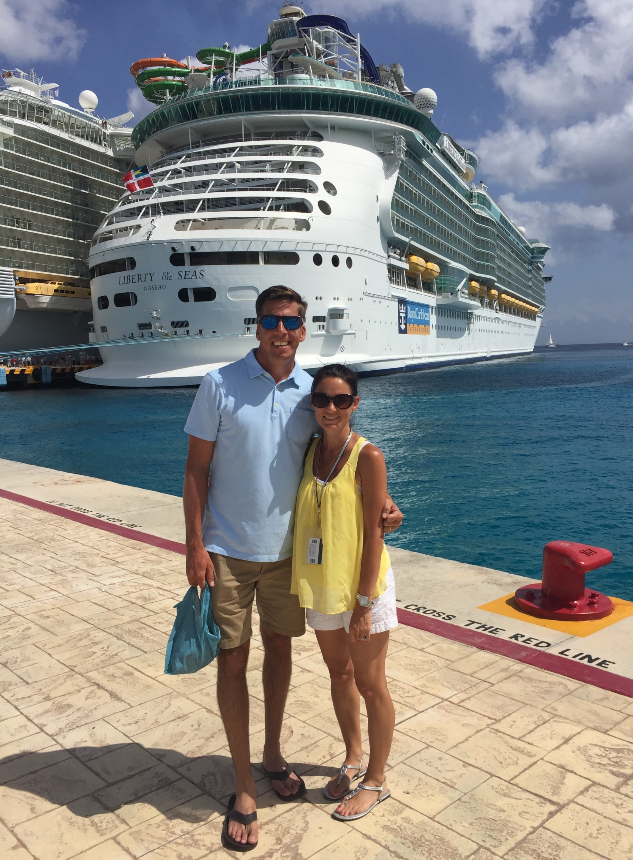 Man and woman in front of a large cruise ship in port