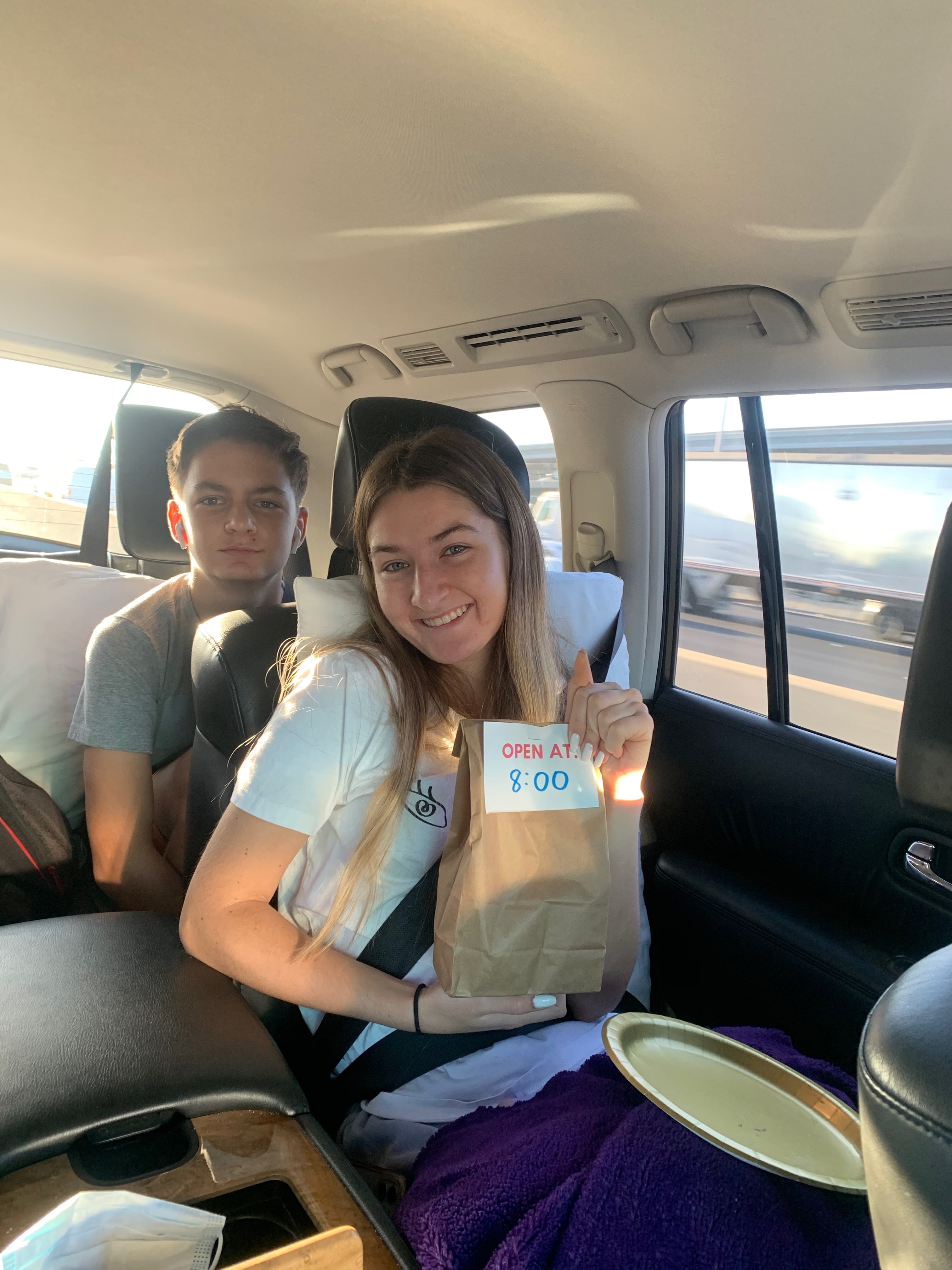 Girl holding road trip goodie bag in the car